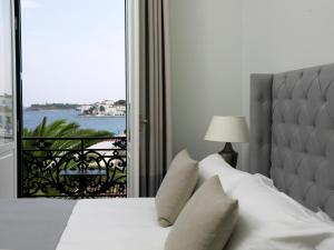 a bedroom with a bed with a large window at Poseidonion Grand Hotel in Spetses