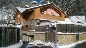 a house covered in snow next to a fence at Pit Stop Cadore in Valle di Cadore