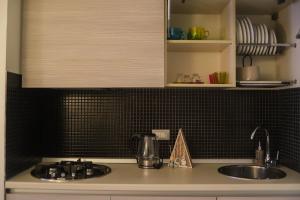 a kitchen counter with a sink and black tiled walls at Suite Rooms in Cosenza