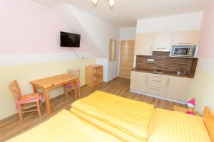 a room with a bed and a table and a kitchen at Penzion U Pešků in Horní Planá