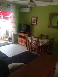 un salon avec une télévision, une table et des chaises dans l'établissement Residencial Jardines Del Mar, à Puerto de Santiago