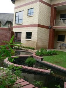 a house with a pond in front of a building at Rustenburg Boutique Hotel in Rustenburg