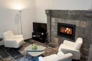 a living room with white chairs and a fireplace at Le Coeur de Durbuy in Durbuy