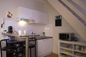 une cuisine avec des placards blancs et un comptoir avec un four micro-ondes dans l'établissement L'Esquile by Cocoonr, à Toulouse