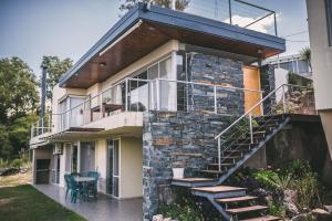 a house with a stone wall and a staircase at lacasonavistalago in Villa Carlos Paz