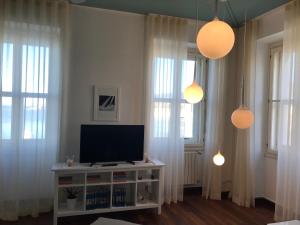 a living room with a tv and two windows at Pep's Rooms by the sea in Trieste