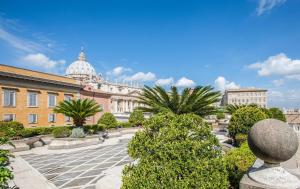 une cour avec des palmiers et un bâtiment dans l'établissement Residenza Paolo VI, à Rome