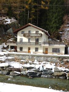 ein Haus im Schnee neben einem Fluss in der Unterkunft Haus Pickelschmiede in Saas-Grund