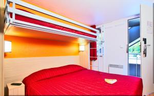 a bedroom with a red bed in a room with a window at Premiere Classe Orange in Orange