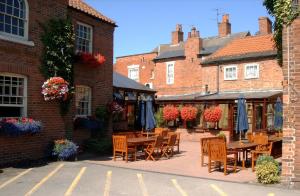 un patio con mesas y sillas frente a un edificio en Millgate House Hotel en Newark upon Trent