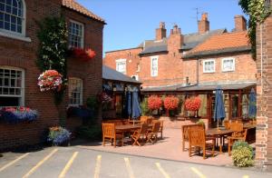 a patio with tables and chairs in front of a building at Millgate House Hotel in Newark-on-Trent