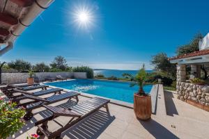 a swimming pool with chaise lounge chairs and the ocean at Villa Jurac in Povljana
