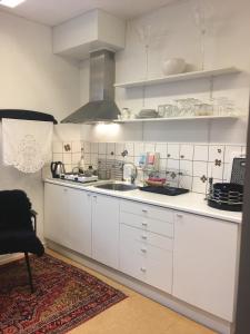 una cocina con armarios blancos y fregadero en Engbo, en Ringkøbing