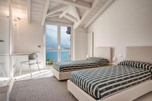 two beds in a room with a large window at Villa Sara Lakeside in Oliveto Lario