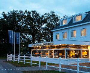 
a white and blue house with a white fence at Fletcher Hotel-Restaurant Het Witte Huis in Amersfoort
