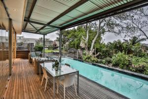 an outdoor deck with a table and chairs and a pool at Sea Dreams Guesthouse in Ballito