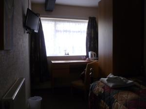 a room with a bed and a window with a desk at Belle Vue Hotel in Llanwrtyd Wells