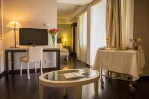 een woonkamer met een bureau, een tv en een tafel bij Grand Hotel Villa Itria Congress & Spa in Viagrande