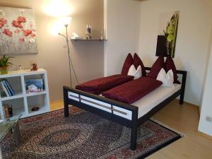 uma cama com almofadas vermelhas numa sala de estar em Just like home em Erding