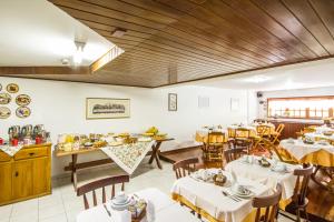 un restaurante con mesas blancas y techos de madera en Pousada Serena, en Campos do Jordão