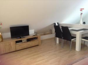 uma sala de estar com uma televisão e uma mesa e cadeiras em Eulennest Oranienburg em Oranienburg
