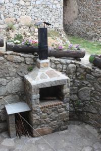 an outdoor brick oven with a bench and flowers at Cal Rosetó in Aransá