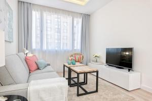 ein Wohnzimmer mit einem Sofa und einem TV in der Unterkunft iloftmalaga Centro Alameda in Málaga
