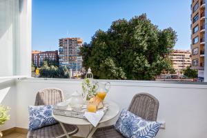 een tafel en stoelen op een balkon met uitzicht op de stad bij iloftmalaga Centro Alameda in Málaga