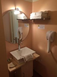 a bathroom with a sink and a mirror and towels at LOGIS Hôtel Le Chantoiseau in Chaumont-sur-Aire