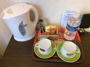 ein Tablett mit zwei Tassen und einer Kaffeekanne auf dem Tisch in der Unterkunft LOGIS Hôtel Le Chantoiseau in Chaumont-sur-Aire