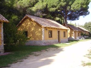 une maison jaune avec un arbre devant elle dans l'établissement Camping Vejer, à Vejer de la Frontera