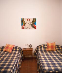 Vivienda Rural El Mirador de Enix في Enix: سريرين في غرفة مع صورة على الحائط