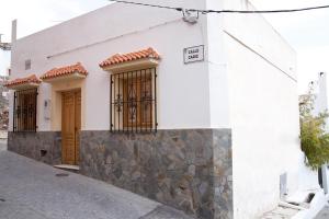 un edificio blanco con puertas marrones y una pared de piedra en Vivienda Rural El Mirador de Enix, en Enix