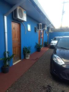 een auto geparkeerd voor een blauw gebouw bij Pousada MG in Foz do Iguaçu