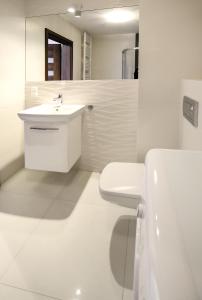 a white bathroom with a toilet and a sink at 100-SIO Apartamenty Budget I in Koszalin