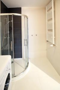 a bathroom with a shower and a washing machine at 100-SIO Apartamenty Budget I in Koszalin