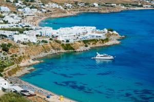 a boat in a body of water with white buildings at Petasos Beach Resort & Spa - Small Luxury Hotels of the World in Platis Yialos Mykonos