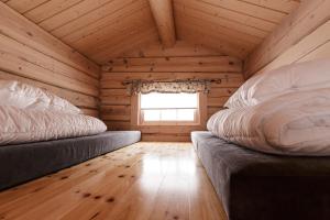 two beds in a log cabin with a window at Røde Kors in Brunstad