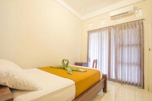 a bedroom with a bed and a window at Putra Dadi Guest House in Canggu