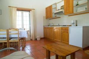 a kitchen with a table and a white refrigerator at Camping / Appartment Coimbrao in Coimbrão