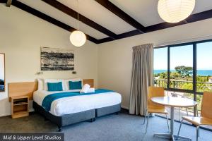 a hotel room with a bed, chair, and table at Kaiteri Motels and Apartments in Kaiteriteri