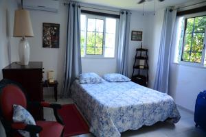 a bedroom with a bed and a chair and windows at Villa Campêche in Les Trois-Îlets