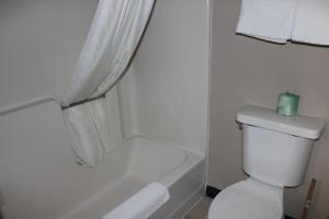 a bathroom with a toilet and a tub with a candle on it at Coratel Inn and Suites Maple Grove in Maple Grove