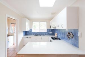 a kitchen with white cabinets and blue tiles at Solhaven in Fremantle