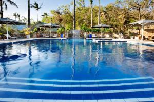 een zwembad in een resort met palmbomen en parasols bij Palm Bay Resort in Long Island