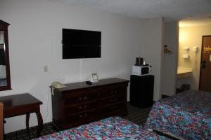 a hotel room with two beds and a dresser and a television at Coratel Inn and Suites Maple Grove in Maple Grove