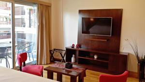 Pokój hotelowy z telewizorem, stołem i krzesłami w obiekcie Aparts Temporarios w BuenosAires