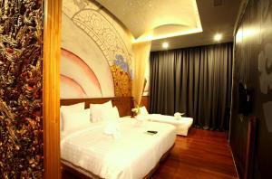 a bedroom with a large white bed with a painting on the wall at Sawasdee Village in Kata Beach