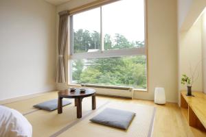 een slaapkamer met een tafel en een groot raam bij Kusatsu Hotel Bekkan Wata no Yu (Adult Only) in Kusatsu