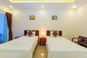 two beds in a room with white walls at Pebble Homestay in Hoi An